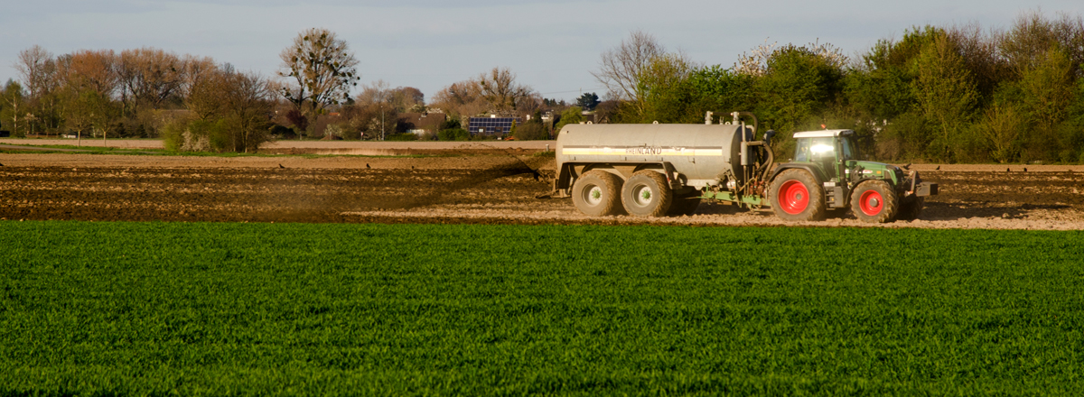 Traktor mit Düngemittelanhänger auf Feld