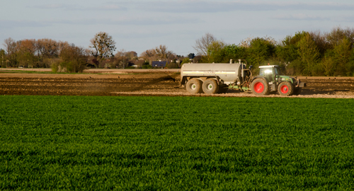 Foto: Traktor mit Düngemittelanhänger auf Feld