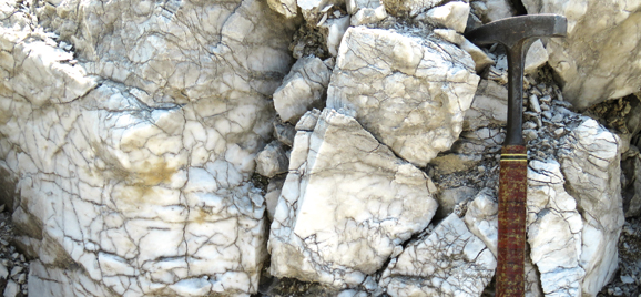 Ausschnitt eines Gipsbrocken mit Hammer: Steinbruch Ellrich (Foto: Thüringer Landesamt für Umwelt, Bergbau und Naturschutz)